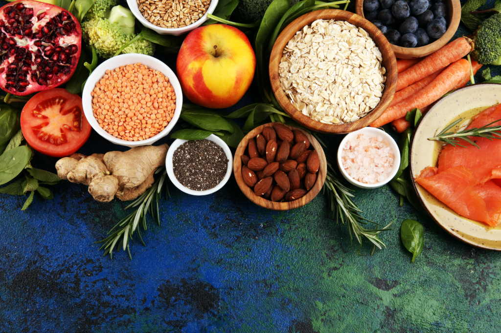 Foto de uma mesa com vários alimentos coloridos, alguns em cumbucas, outros em pratos ou na mesa.