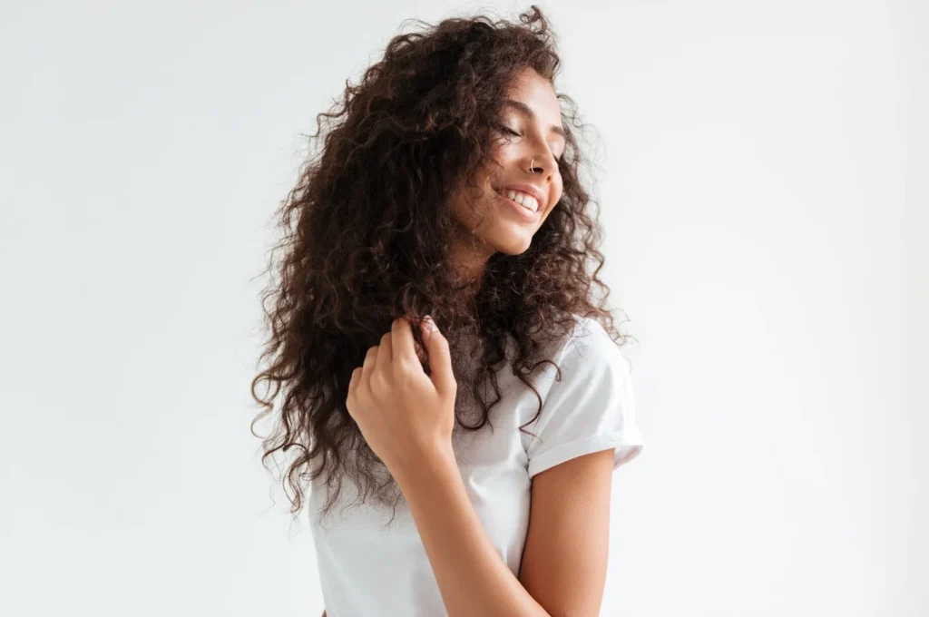 mulher-com-cabelos-cacheados-sorrindo-de-olhos-fechados